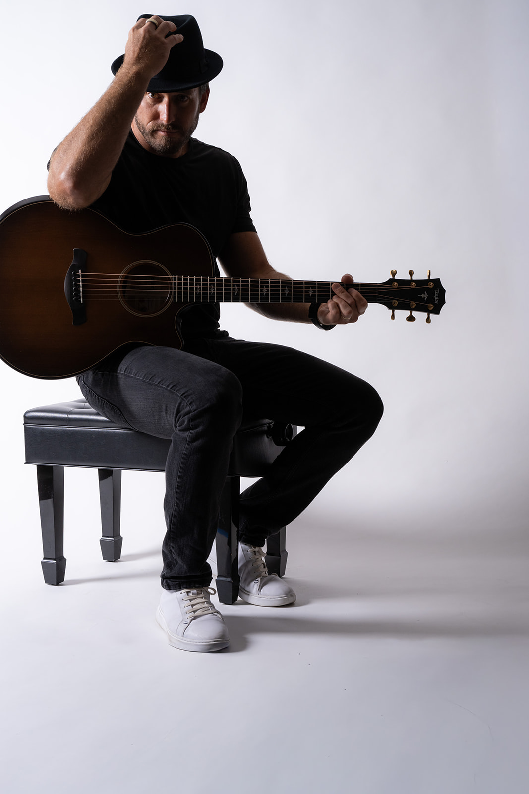 Ryan Hiller portrait with acoustic guitar and hat