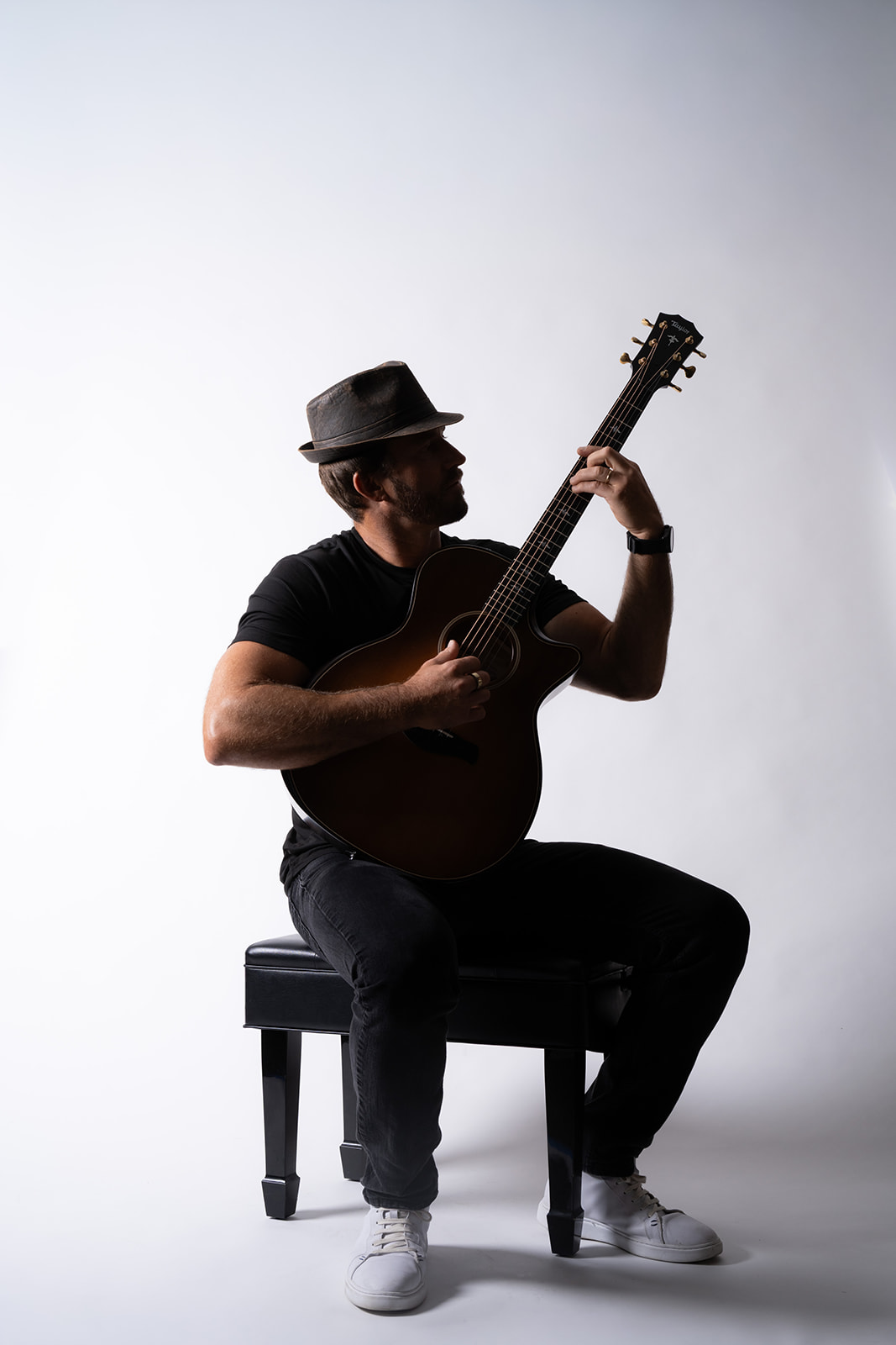 Ryan Hiller seated with an acoustic guitar in side profile