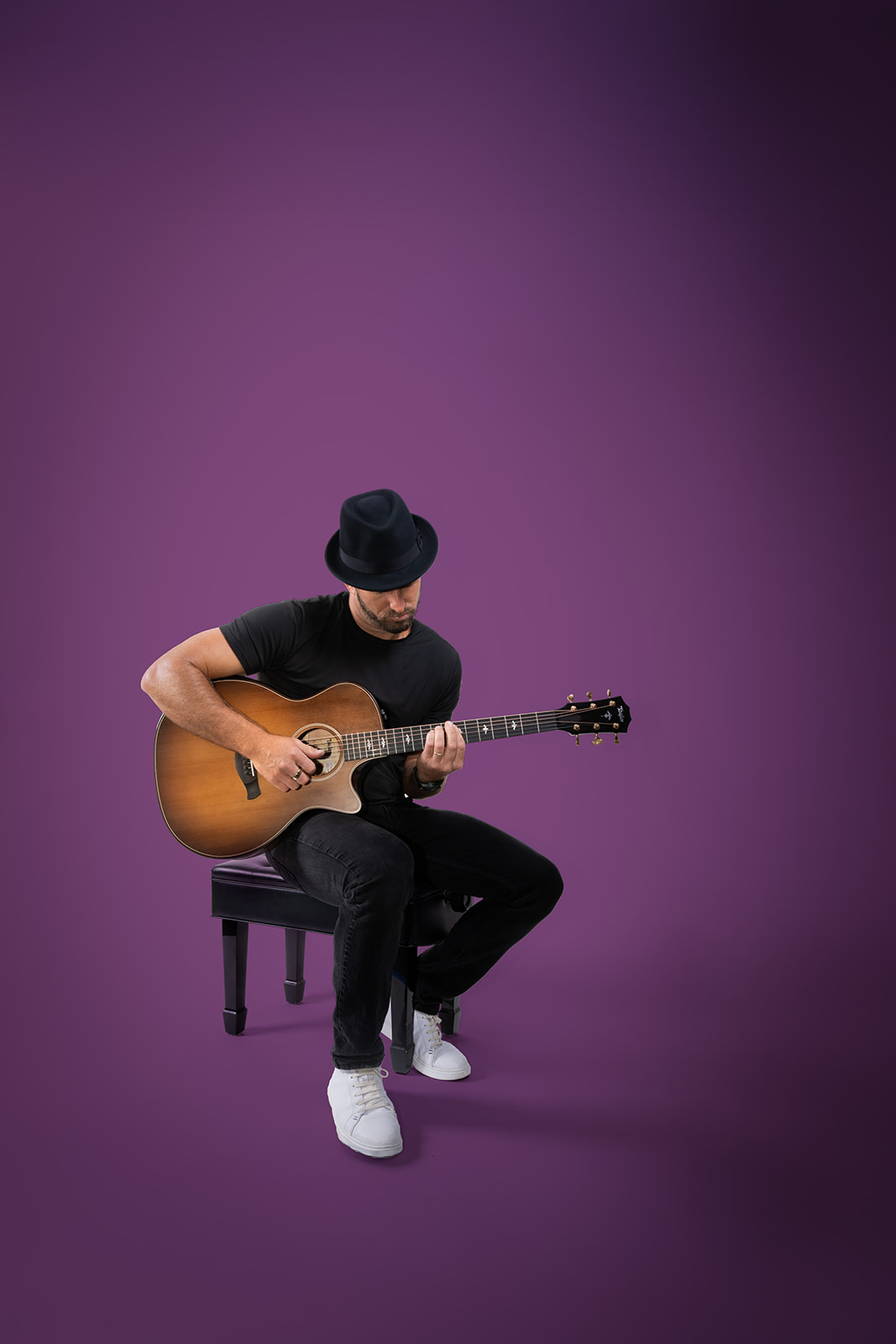 Ryan Hiller playing guitar against a purple background